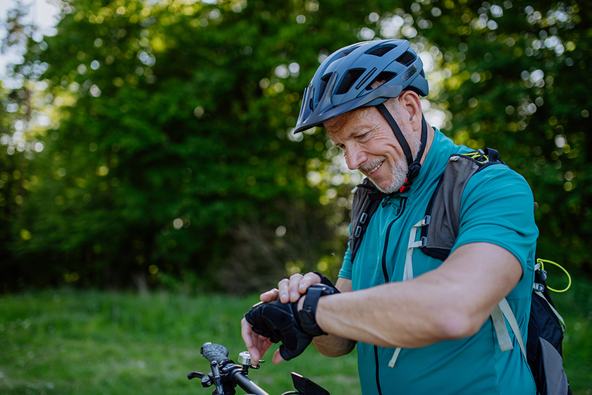 An active senior man riding bicycle at summer park