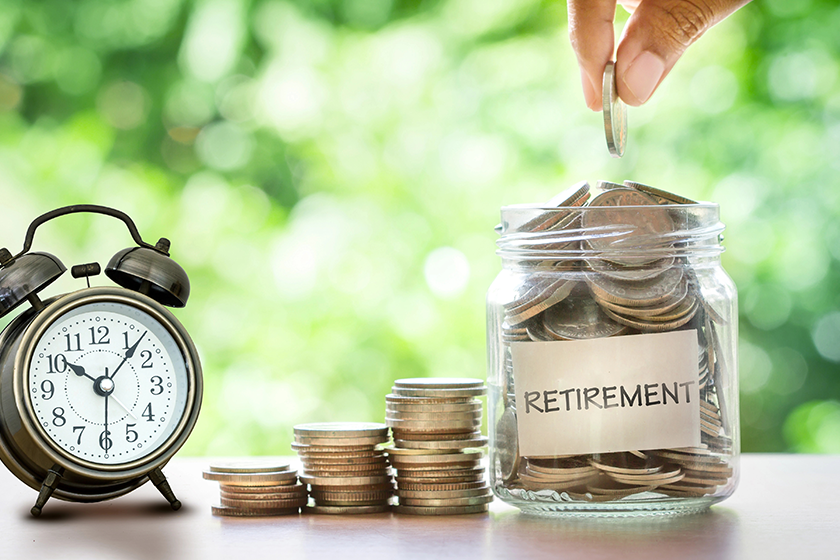 Hand putting Coins in glass jar with retro alarm clock